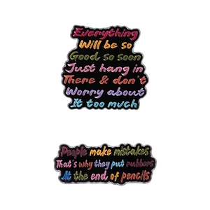 Two black enamel letter pins with colorful motivational quotes on a white background