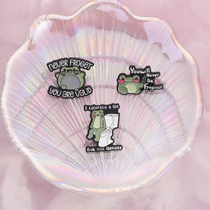 Three cute cartoon frog metal badges with funny quotes on a shell tray jewelry holder