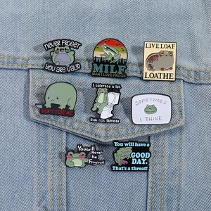 Detailed view of eight humorous cartoon frog enamel pins displayed on a denim jacket pocket