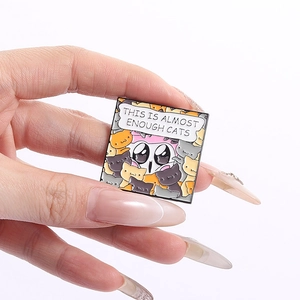 Detail of square enamel pin featuring cartoon cats and text This Is Almost Enough Cats