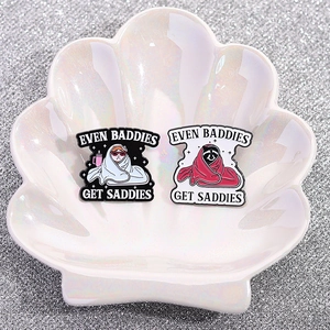 Skeleton style enamel pins featuring a cat and raccoon with 'Even Baddies Get Saddies' text