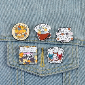 Detail of five funny cartoon cat enamel pins pinned on a light blue denim jacket pocket