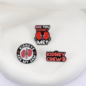 Three medical kidney anatomy enamel pins with funny puns on white display stand