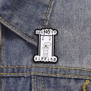 Detail showing 'say NO to KIPPING' enamel pin pinned on dark blue denim fabric