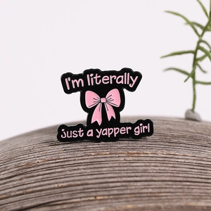 Pin de esmalte con lazo rosa y texto GIRL sobre una superficie de madera natural