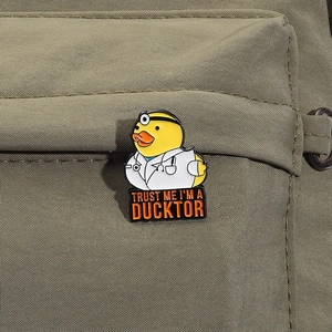 Spilla smaltata a forma di papera dottore con testo Trust Me I'm a Ducktor su borsa
