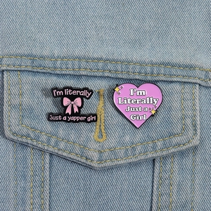 Detalle de pines esmaltados de lazo rosa y corazón lila en bolsillo de vaquero