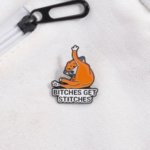 Orange cat enamel pin with elizabeth collar and Bitches Get Stitches text on canvas