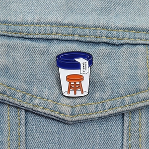Close-up of stool sample enamel pin featuring a clever medical pun on denim jacket