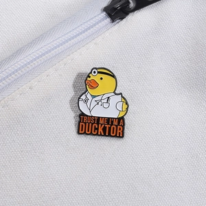 Spilla smaltata con papera dottore e scritta 'Trust Me I'm a Ducktor' su tela