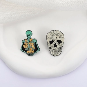 Detail of two Halloween enamel cat skeleton pins showing fine zinc alloy metal craftsmanship