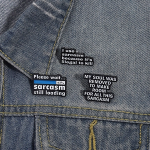 Detail von sarkastischen Emaille-Pins an einem blauen Jeansjacken-Kragen