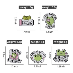 Detailansicht von fünf grünen Emaille-Pins mit Frosch-Motiven und Sprüchen zur Psyche