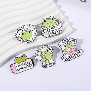 Set aus 5 süßen Frosch-Emaille-Pins mit Motivationssprüchen auf weißem Hintergrund