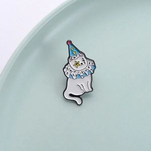 Cartoon enamel pin featuring a white cat with party hat and clown ruffle on a green plate