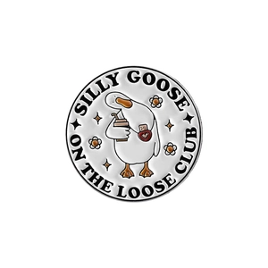 Detail of round enamel pin with a cartoon goose holding coffee and club text