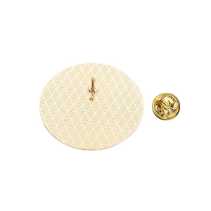 Détail du revers d'un badge rond en métal doré avec texture quadrillée et fermoir papillon