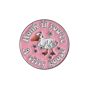 Detail of pink enamel badge showing a white cartoon goose and Honk if you are silly goose text