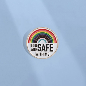 Badge émaillé arc-en-ciel avec texte « YOU ARE SAFE WITH ME » sur fond bleu clair