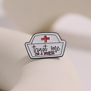 Nurse hat enamel pin featuring Trust Me I'm A Nurse text and red cross on minimalist prop