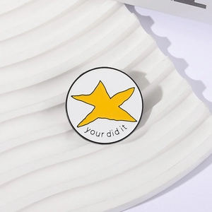 Détail macro du pin's émaillé rond avec étoile jaune et texte motivant You Did It
