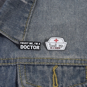 Detail of medical doctor and nurse enamel pins pinned on denim jacket fabric texture