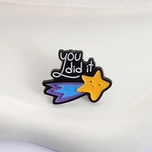 Macro detail of enamel meteor brooch featuring YOU did it text and smiling yellow star