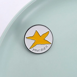 Gros plan d'une broche en émail blanc avec étoile et texte Your Did It sur assiette