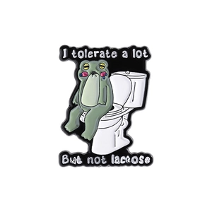 Close-up of funny frog on toilet enamel pin with I tolerate a lot but not lactose text