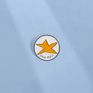 Badge rond en métal avec étoile jaune et texte 'you did it' sur fond bleu clair