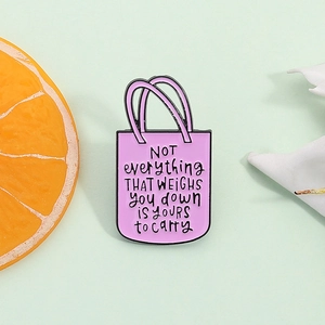 Broche en émail sac violet avec citation inspirante sur fond vert clair