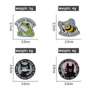 Detail view of humorous animal enamel pins featuring a frog and cat with knives