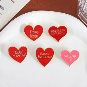Set di cinque spille smaltate a cuore con bordi dorati e scritte romantiche in vassoio