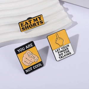 Three yellow enamel pins with fun slogans like 'Eat My Shorts' on a wavy display
