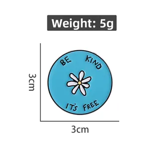 Détail d'une broche marguerite de 3cm avec citation BE KIND et indication de poids 5g