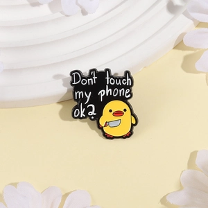 Detail of funny yellow duck brooch with knife and Don't touch my phone ok text