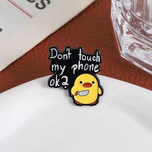 Cute yellow duck enamel pin with 'Don't touch my phone ok' text on white ceramic plate