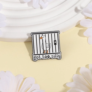 Funny white goose in black cage enamel pin with 'got too silly' text on beige background
