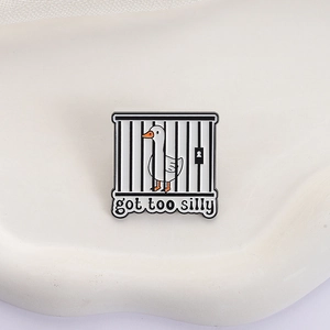 Cartoon white duck in cage enamel pin with 'got too silly' text on a stone base
