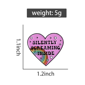 Detail view of heart enamel pin with Silently Screaming Inside text and rainbow graphics
