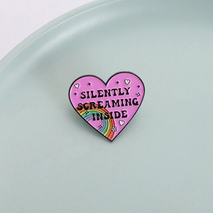 Pink heart enamel pin with Silently Screaming Inside text and rainbow accent