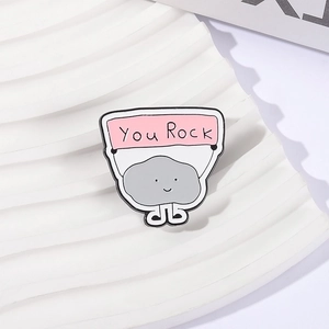 Cute cartoon stone enamel pin with You Rock sign on a white textured stand