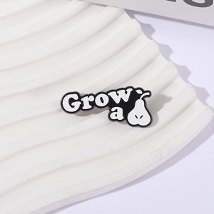 Minimalist monochrome enamel pear brooch with 'Grow a' text on a wavy display base