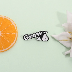 Minimalist 'Grow a Pear' enamel brooch with letter and fruit motif on a green background