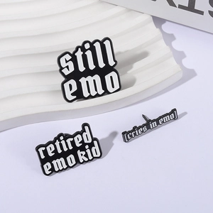 Three-piece set of black and white Still Emo metal enamel pins on a white display stand