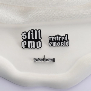 Detailed close-up of three black and white emo quote enamel pins on white wave decor