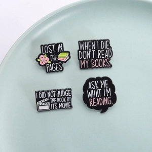 Set of four bookworm enamel pins with reading quotes on a clean decorative plate