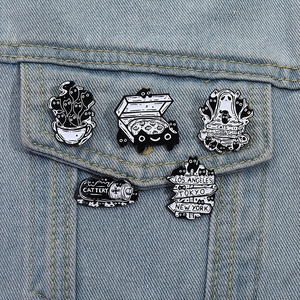 Close-up of five black and white enamel cat pins on a blue denim jacket pocket