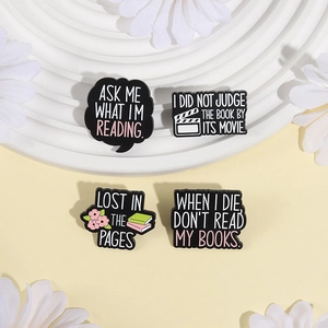 Set of 4 minimalist enamel book pins with reading quotes on a decorative plate