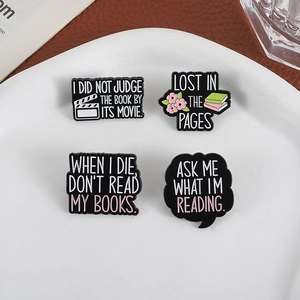 Lot de quatre broches en émail sur les thèmes du livre et du cinéma sur une assiette